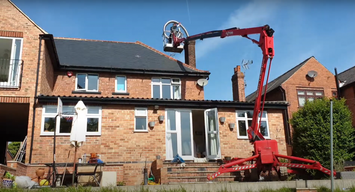 Photo shows big red cherrypicker, helping to install a chimney liner on a sunny day 